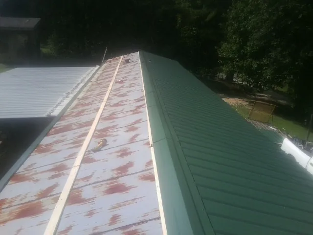 Old rusted panels beside newly installed green metal roofing — Wind Damage Roof Repair by Roofing Brothers in Bedford