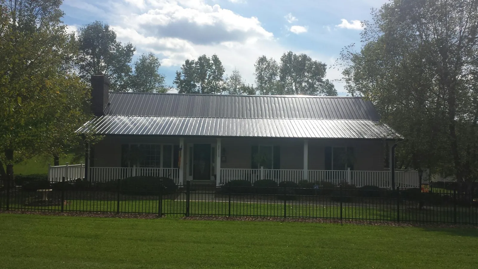 Gray metal roof on a brick ranch with a full width front porch — Gutter Guard Installation work by our crew in Bedford
