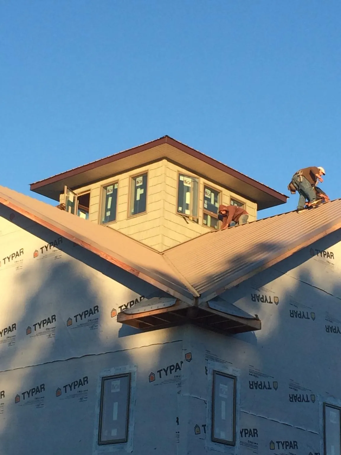 Roofers working around a rooftop cupola on a new metal roof at sunset — Roof Waterproofing in Bedford by Roofing Brothers